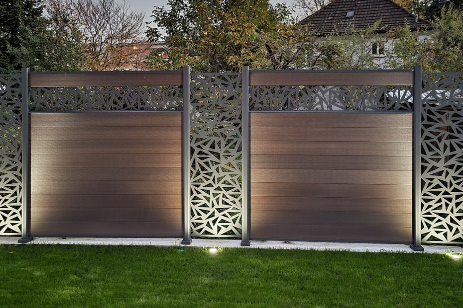 Moderner WPC-Platinum-Sichtschutz mit dekorativen Elementen, davor Grünfläche, ausgestattet mit integrierter Bodenbeleuchtung, HolzLand