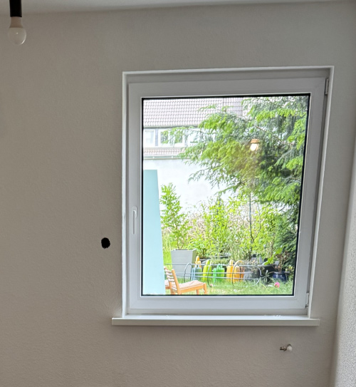 Durch das Fenster der renovierten Wohnung fällt der Blick direkt in den grünen Garten, HolzLand Beese Unna