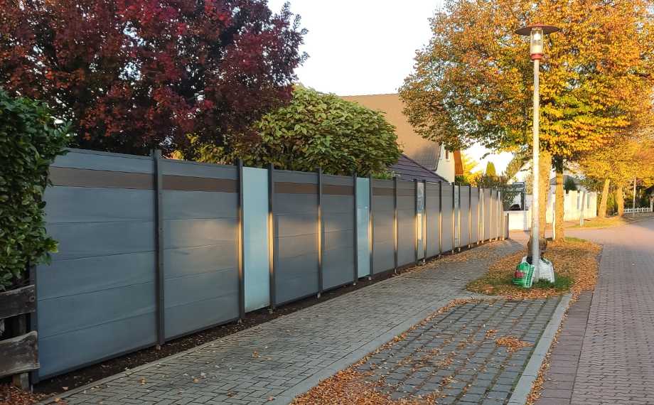WPC-Zaun am Straßenrand mit matten Glaselementen, HolzLand Beese Unna